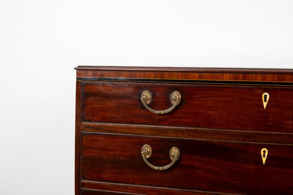 A nineteenth-century mahogany chest of five drawers featuring brass drop handles, keyhole escutcheons, and a shaped lower apron. View III