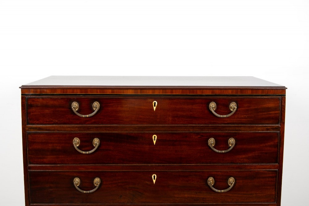 A nineteenth-century mahogany chest of five drawers featuring brass drop handles, keyhole escutcheons, and a shaped lower apron. View IV