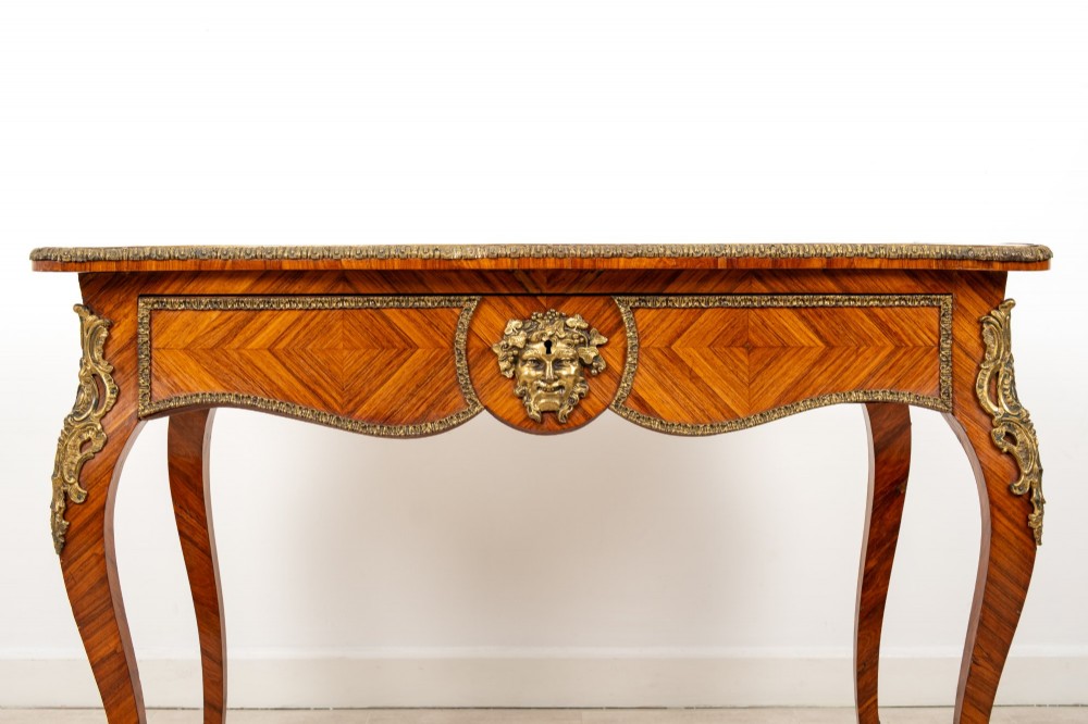 A late 19th-century French kingwood bureau plat featuring a red leather inset top, geometric parquetry veneer, ormolu mounts, and cabriole legs. View V