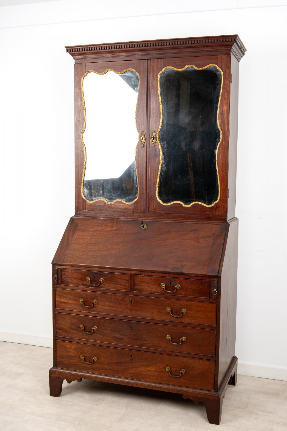 An eighteenth-century mahogany bureau bookcase featuring shaped mirrored double doors on the upper cabinet, a slant-front desk midsection, and four graduated drawers below with brass drop handles. View II