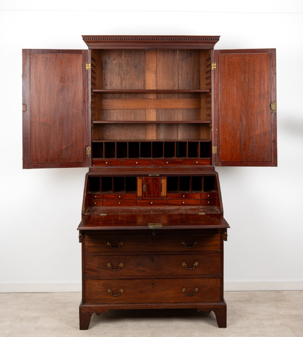 An eighteenth-century mahogany bureau bookcase featuring shaped mirrored double doors on the upper cabinet, a slant-front desk midsection, and four graduated drawers below with brass drop handles. View VII