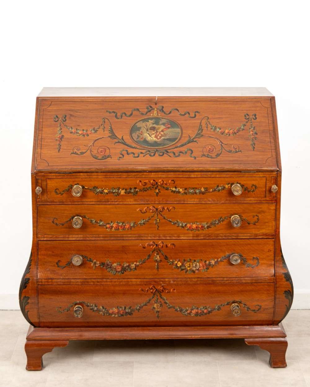 An Edwardian satinwood slant-front bureau with hand-painted floral swags, ribbon garlands, four drawers, and bracket feet. View II