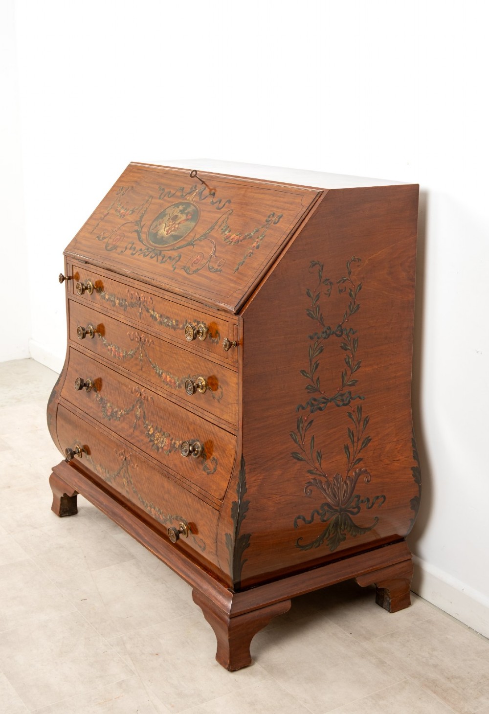 An Edwardian satinwood slant-front bureau with hand-painted floral swags, ribbon garlands, four drawers, and bracket feet. View IV