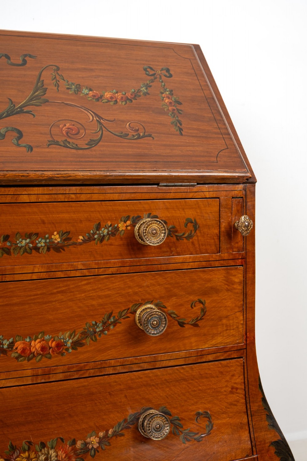 An Edwardian satinwood slant-front bureau with hand-painted floral swags, ribbon garlands, four drawers, and bracket feet. View VII