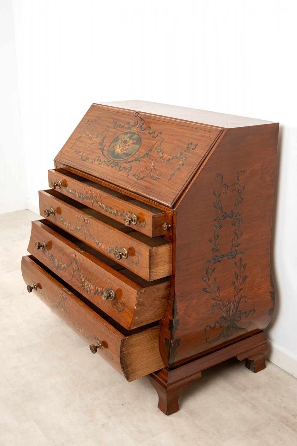 An Edwardian satinwood slant-front bureau with hand-painted floral swags, ribbon garlands, four drawers, and bracket feet. View IX