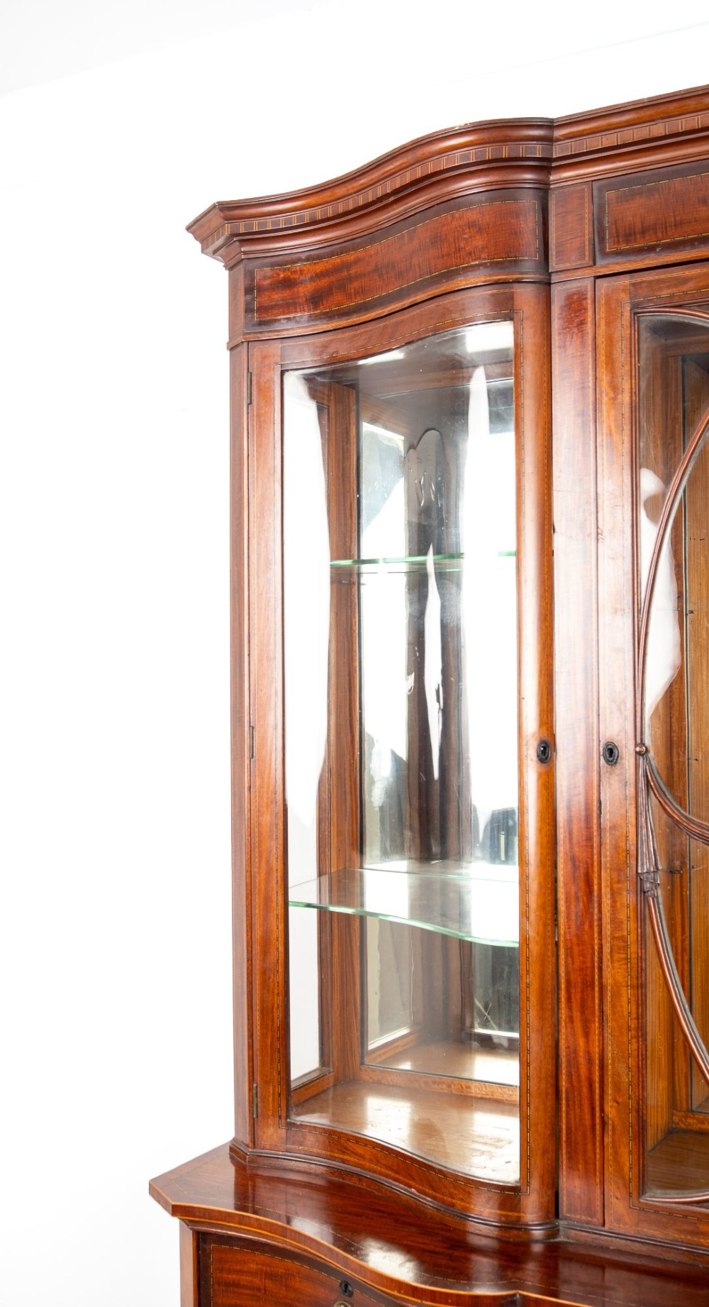 An Edwardian mahogany serpentine display cabinet featuring a central glazed door with geometric astragal glazing, glass side panels, and a hand-painted floral landscape panel on the lower central door. View VI