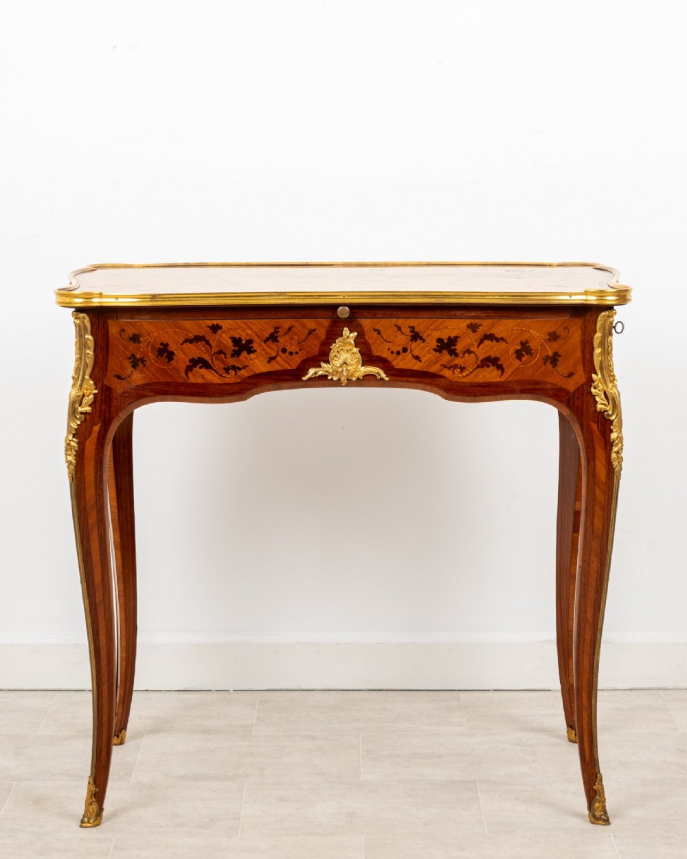 A French Louis XV style kingwood bureau plat featuring floral marquetry inlay, curved cabriole legs, and gilt-bronze mounts.