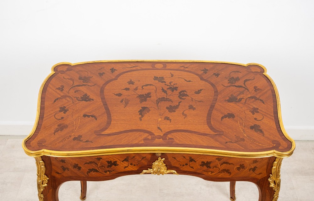 A French Louis XV style kingwood bureau plat featuring floral marquetry inlay, curved cabriole legs, and gilt-bronze mounts. View VI