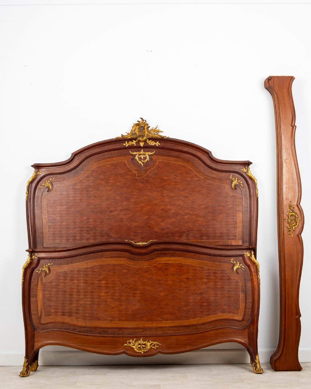An antique French Louis XV style bedstead crafted from kingwood with geometric parquetry veneers and gilded bronze ormolu mounts. View II