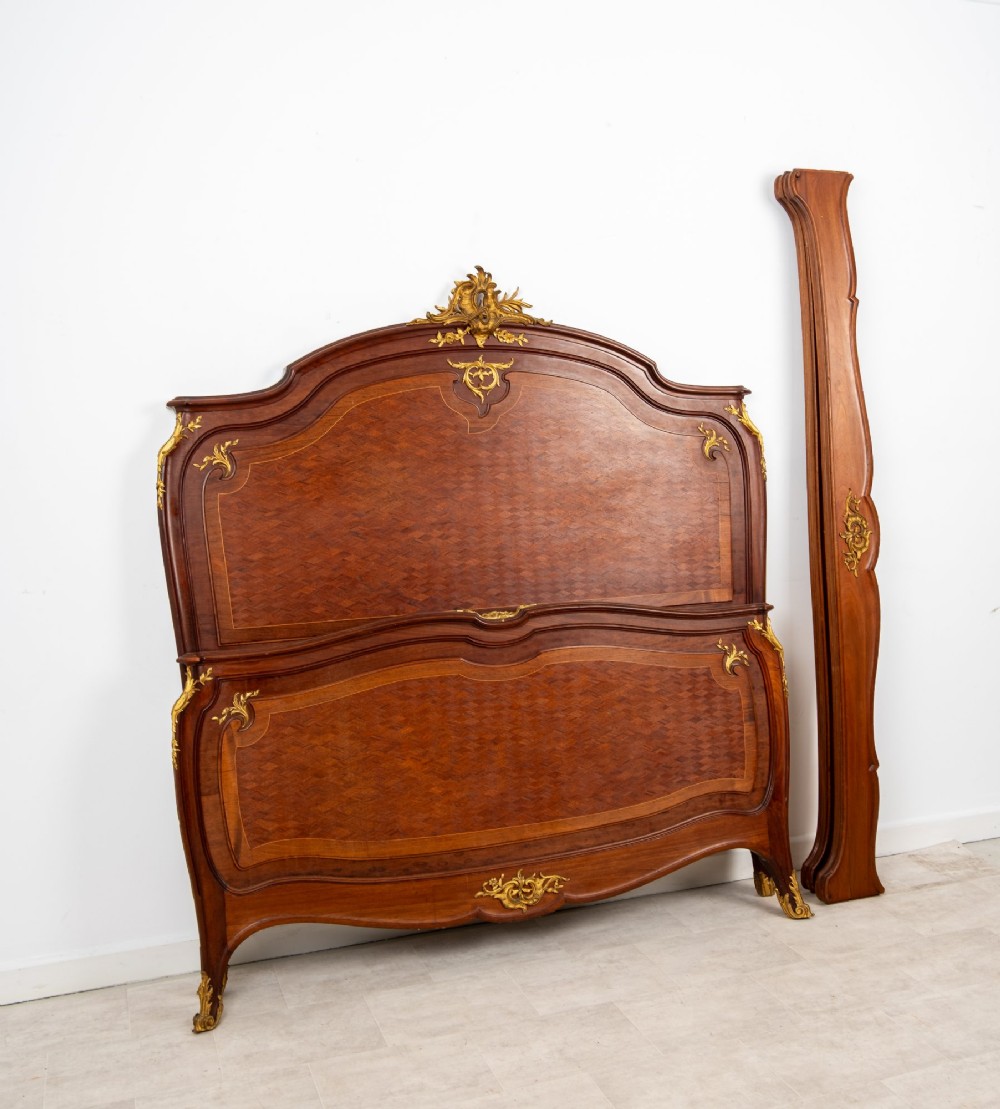An antique French Louis XV style bedstead crafted from kingwood with geometric parquetry veneers and gilded bronze ormolu mounts. View X