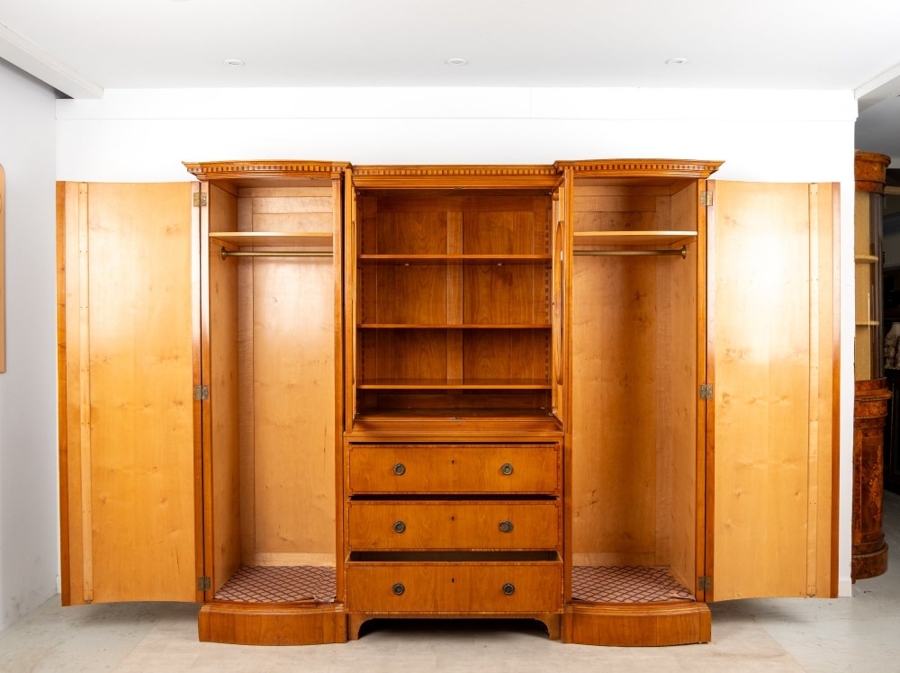 An Edwardian satinwood breakfront compactum wardrobe featuring central glazed doors, three drawers, and flanking bow-front cupboards decorated with hand-painted oval medallions. View VII