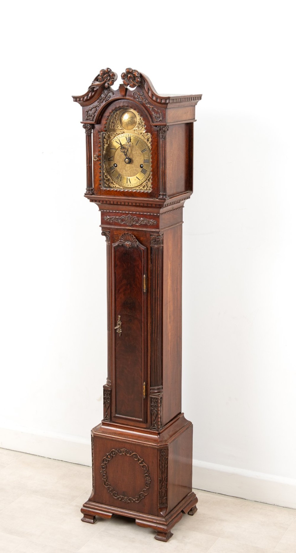 An Edwardian mahogany grandmother clock with a carved swan neck pediment, a brass dial with Roman numerals, and a slim waist door. View III