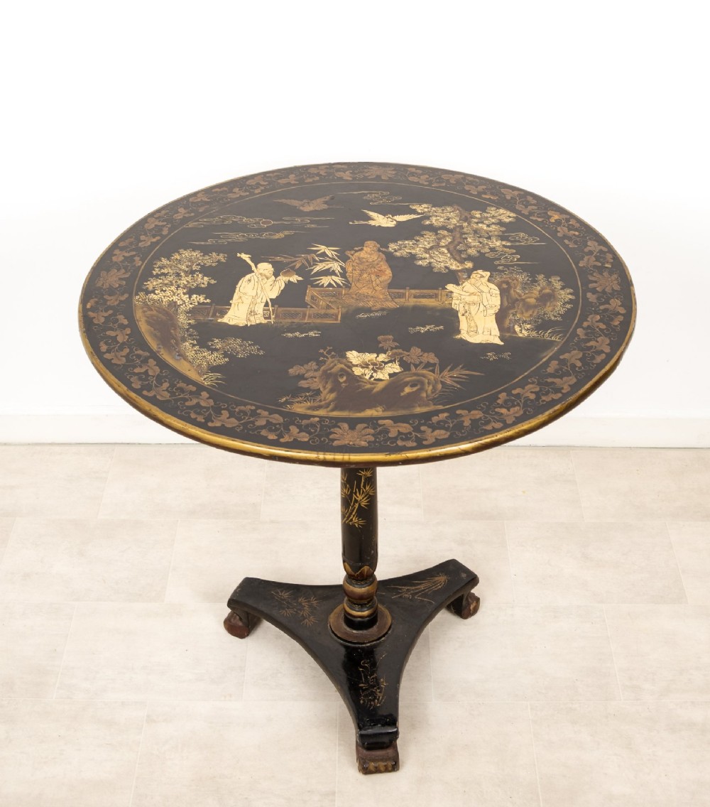 A circular black lacquer tilt-top table decorated with gilded Chinese figures, flora, and fauna on a turned pedestal tripod base. View IV