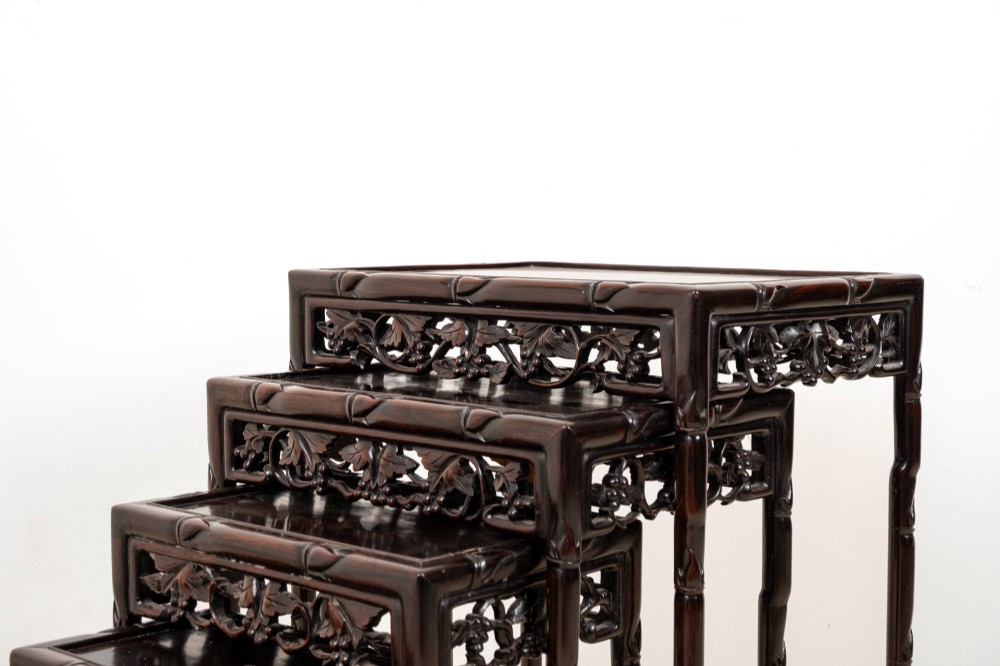 A set of four dark hardwood nested side tables featuring carved faux bamboo legs and openwork carved aprons, shown arranged in a graduated stepped stack. View IV