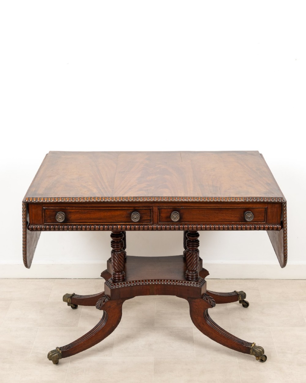 A 19th-century mahogany drop-leaf sofa table with four spiral-turned column supports, frieze drawers, and splayed legs on brass castors. View III