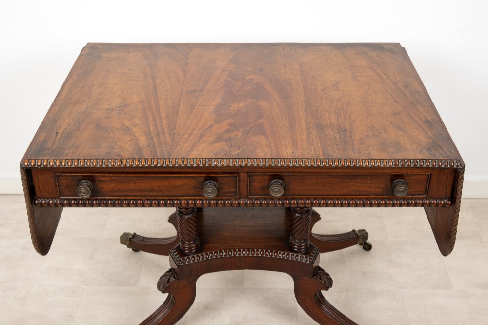 A 19th-century mahogany drop-leaf sofa table with four spiral-turned column supports, frieze drawers, and splayed legs on brass castors. View IV