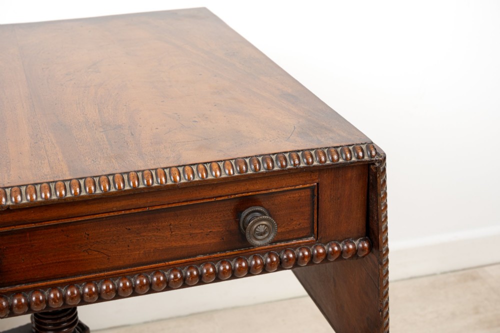 A 19th-century mahogany drop-leaf sofa table with four spiral-turned column supports, frieze drawers, and splayed legs on brass castors. View V