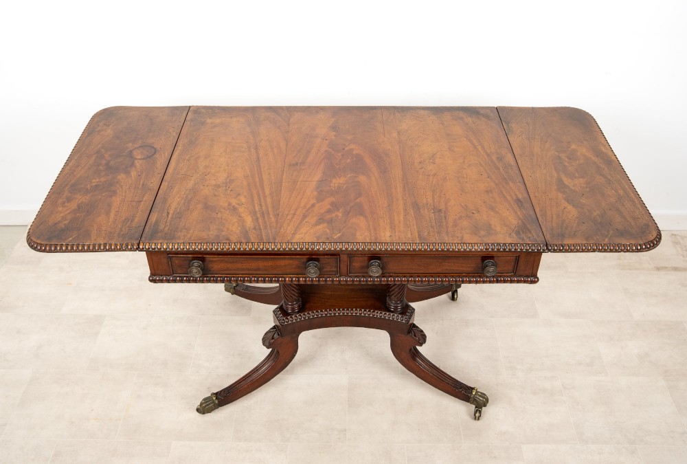 A 19th-century mahogany drop-leaf sofa table with four spiral-turned column supports, frieze drawers, and splayed legs on brass castors. View IX