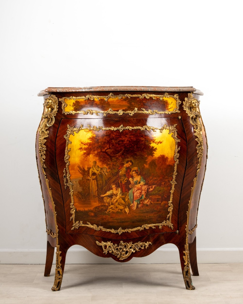 An antique French Vernis Martin bombe cabinet featuring hand-painted pastoral scenes on a curved door, ornate gilt-bronze mounts, and a marble top.