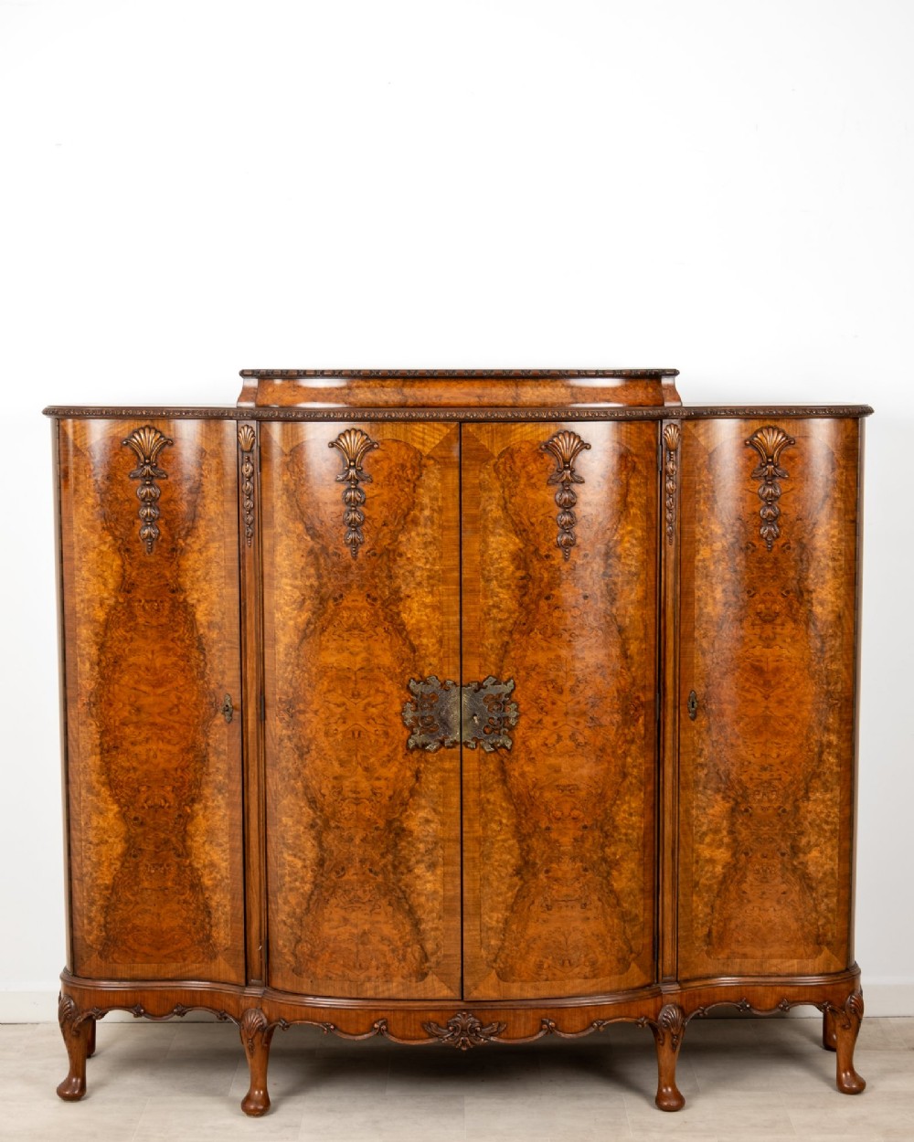 A 1930s burr walnut cocktail cabinet with book-matched veneers, carved shell motifs, brass hinges, and cabriole legs. View II
