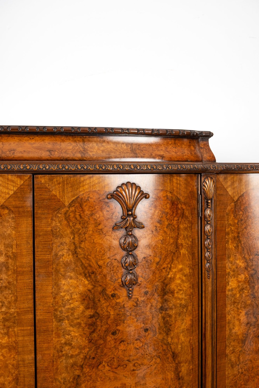 A 1930s burr walnut cocktail cabinet with book-matched veneers, carved shell motifs, brass hinges, and cabriole legs. View V