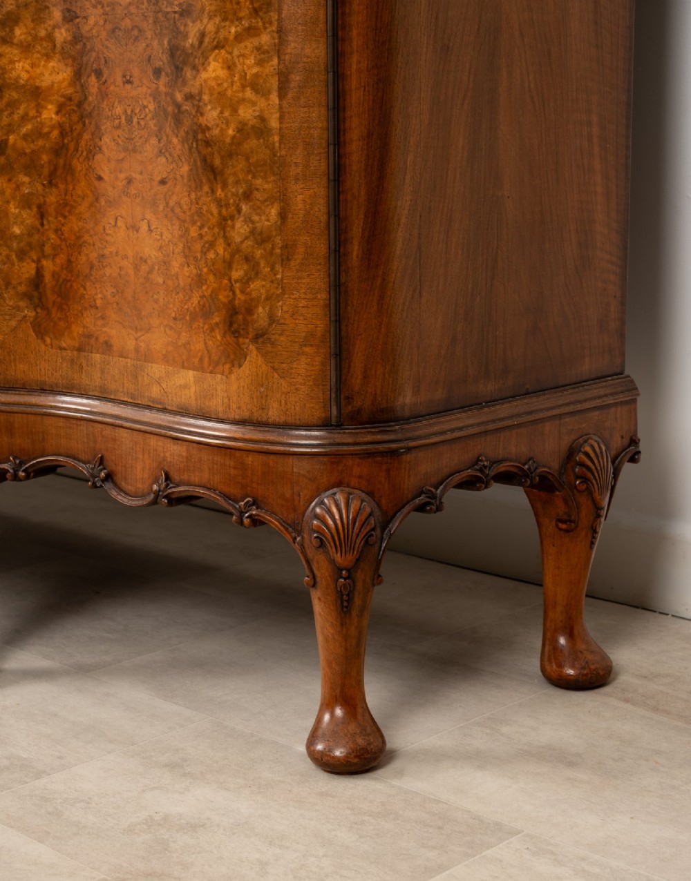 A 1930s burr walnut cocktail cabinet with book-matched veneers, carved shell motifs, brass hinges, and cabriole legs. View VII
