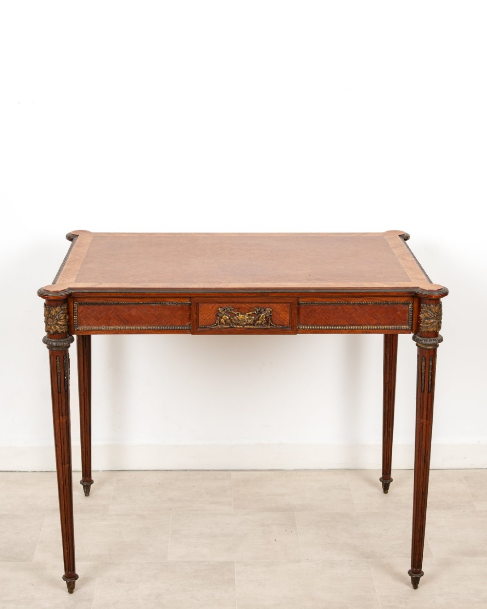 An antique French kingwood writing table featuring geometric parquetry, a single central drawer with ormolu mounts, and four tapered fluted legs. View II