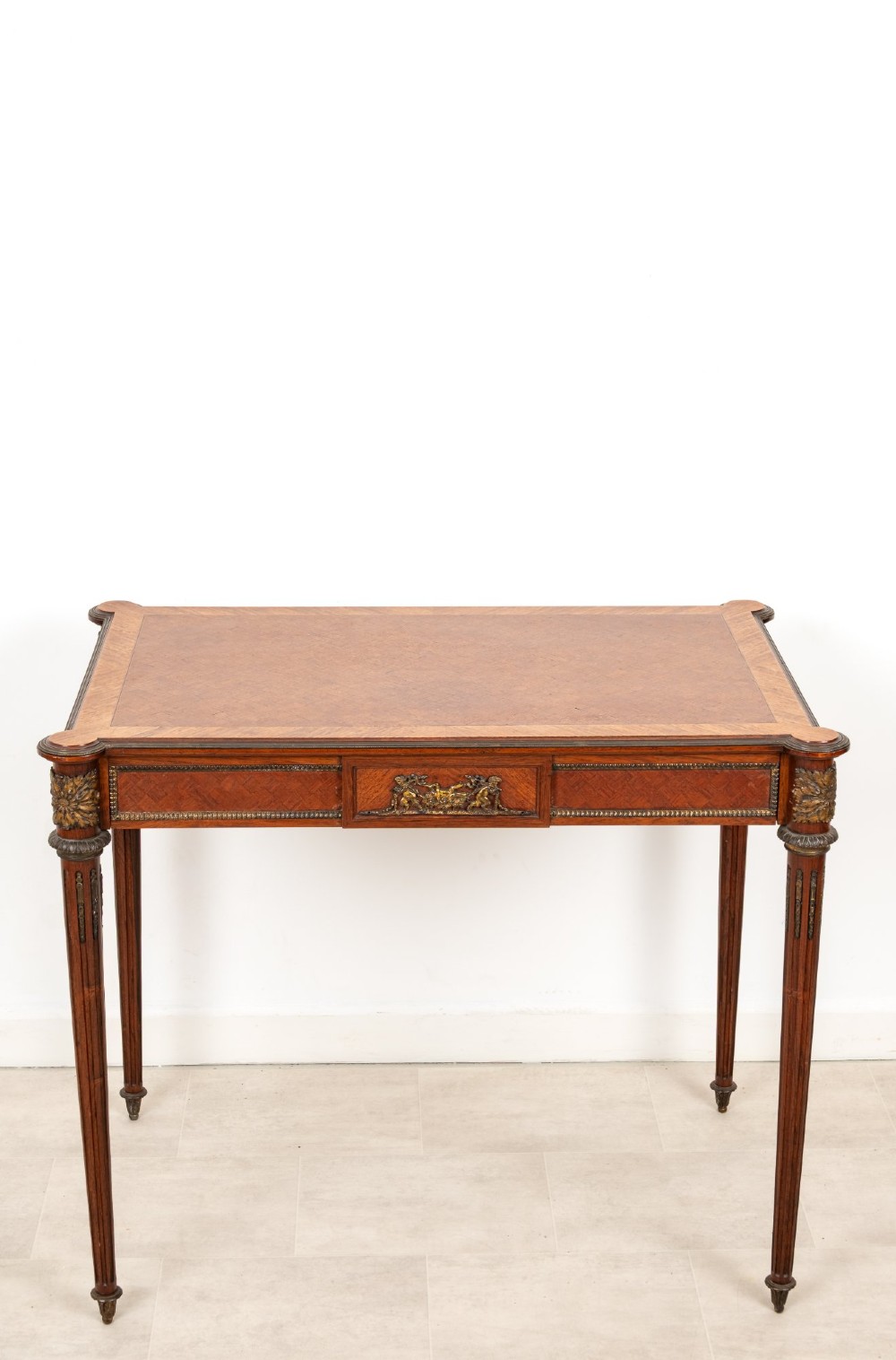 An antique French kingwood writing table featuring geometric parquetry, a single central drawer with ormolu mounts, and four tapered fluted legs. View III