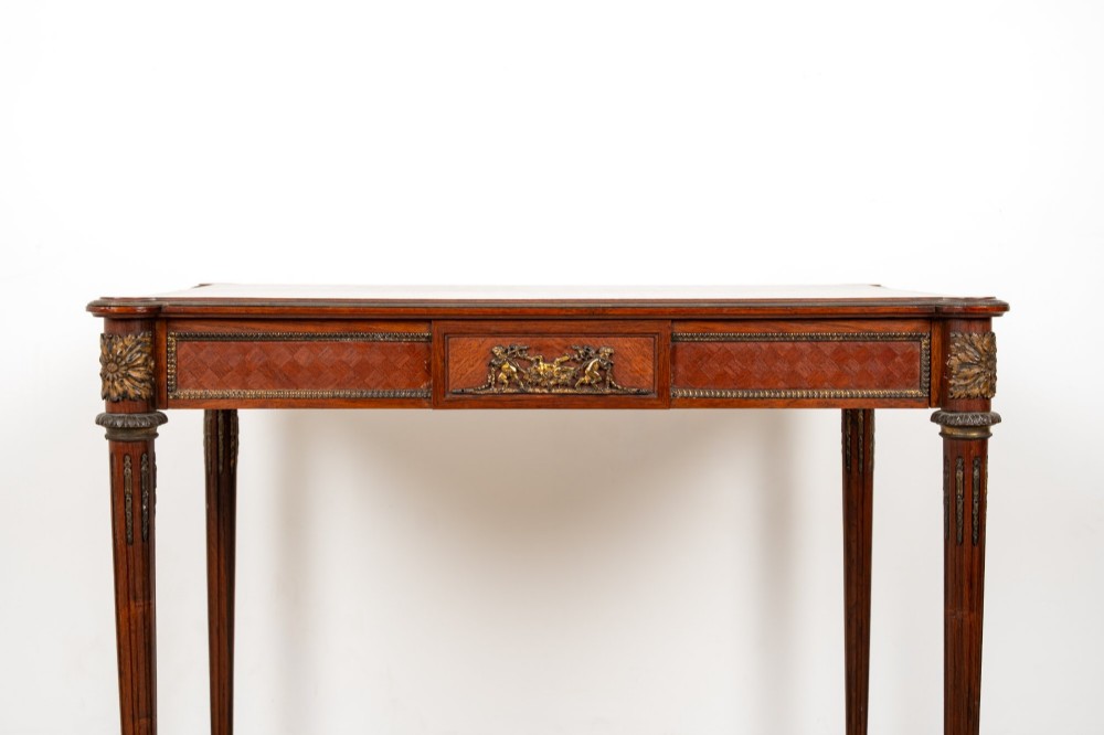 An antique French kingwood writing table featuring geometric parquetry, a single central drawer with ormolu mounts, and four tapered fluted legs. View IV