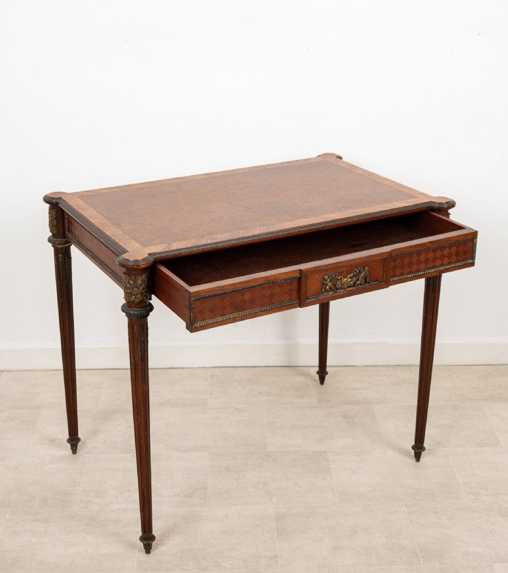 An antique French kingwood writing table featuring geometric parquetry, a single central drawer with ormolu mounts, and four tapered fluted legs. View VII