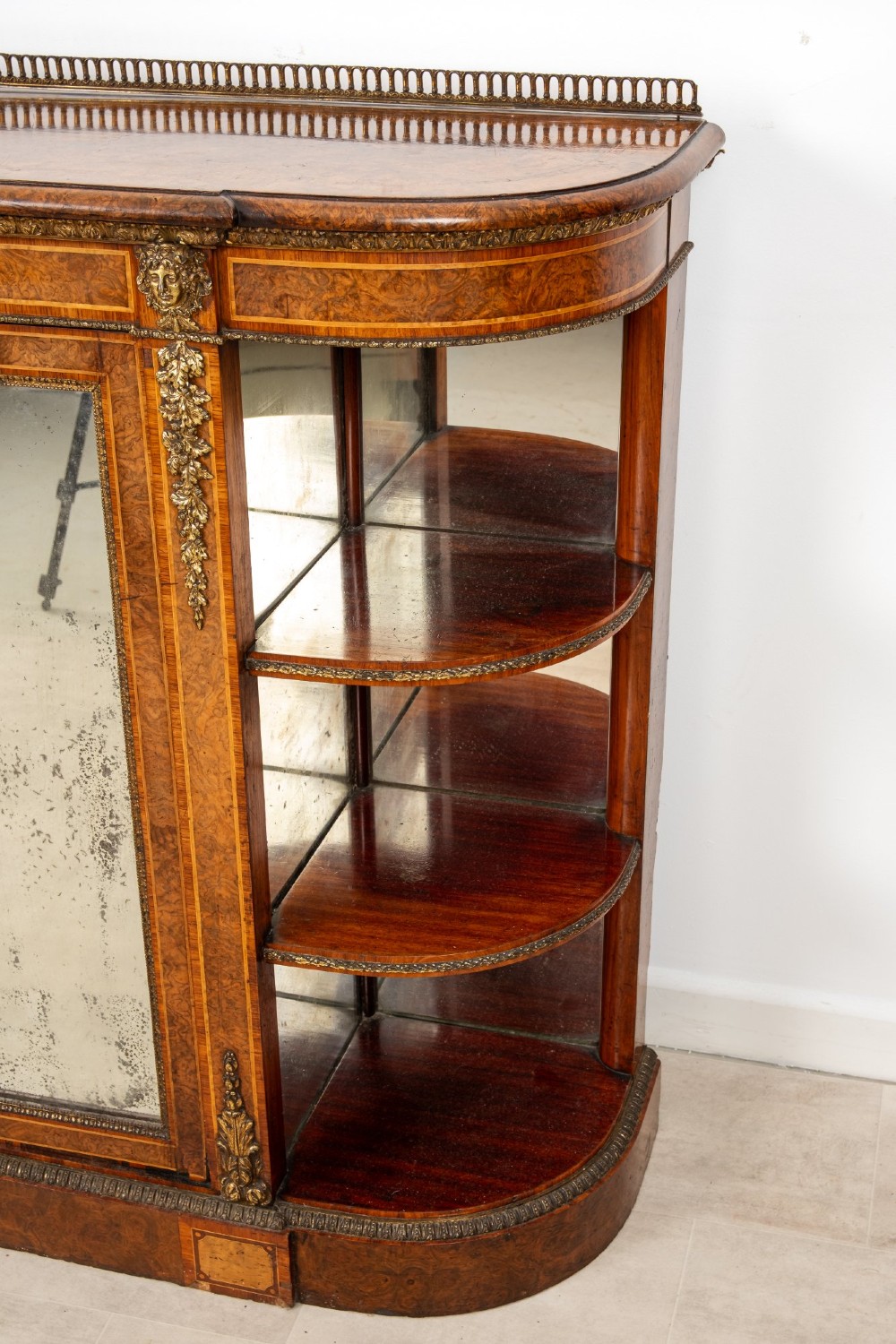 A Victorian burr walnut credenza featuring central mirrored doors, open curved side shelves, and detailed gilt ormolu mounts. View V