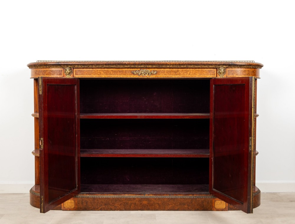 A Victorian burr walnut credenza featuring central mirrored doors, open curved side shelves, and detailed gilt ormolu mounts. View IX