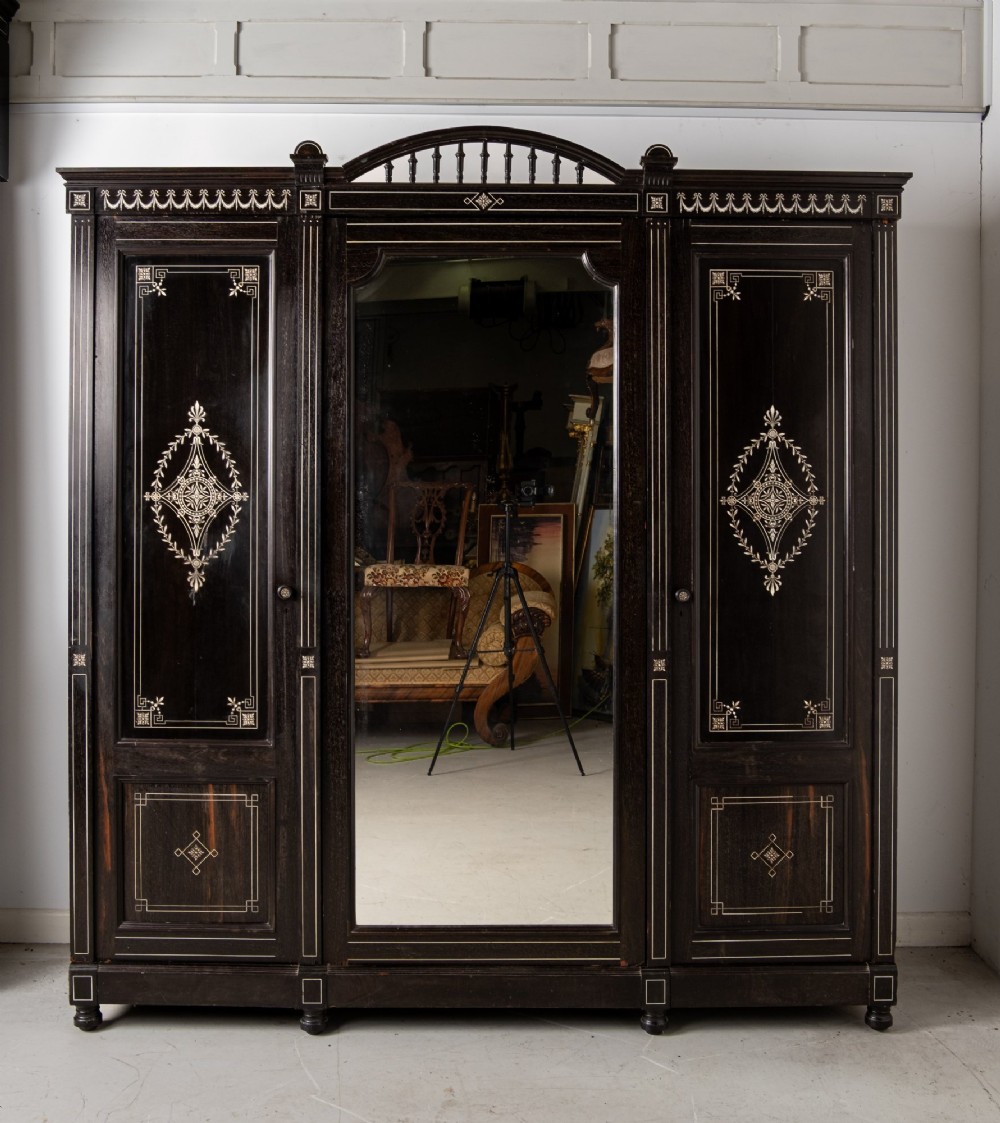A six-piece late Victorian ebonised bedroom suite featuring bone inlay, comprising a half-tester bed, mirror wardrobe, dressing table, marble-top washstand, nightstand, and towel rail. View V