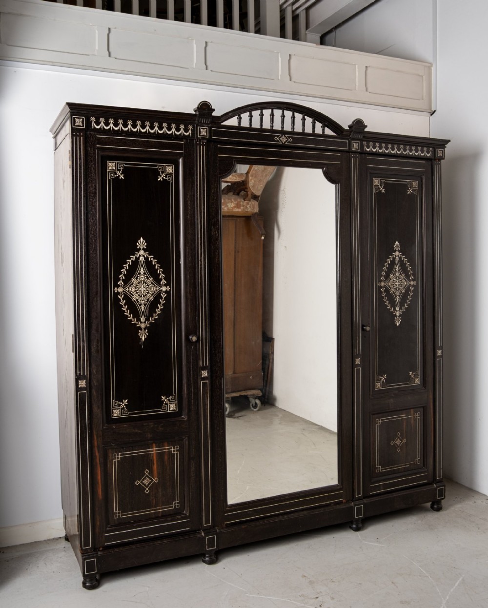 A six-piece late Victorian ebonised bedroom suite featuring bone inlay, comprising a half-tester bed, mirror wardrobe, dressing table, marble-top washstand, nightstand, and towel rail. View VI