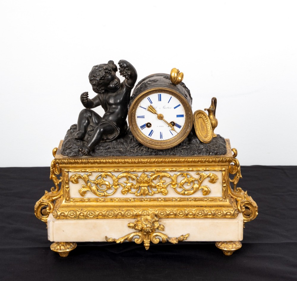 A French 19th-century figural mantel clock with a patinated bronze cherub beside a circular white enamel dial on a gilt-bronze and marble base. View III
