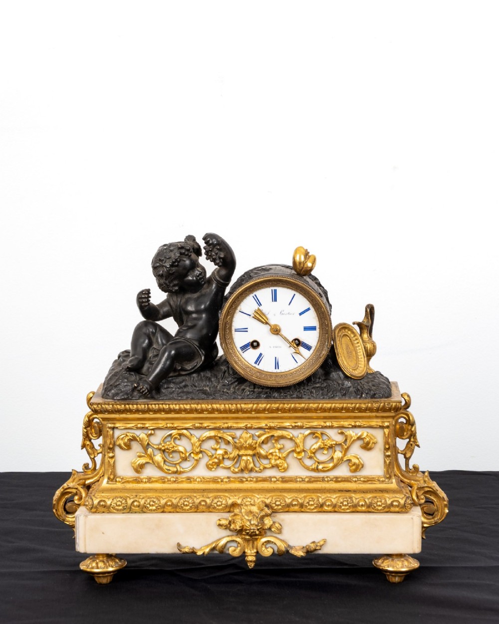 A French 19th-century figural mantel clock with a patinated bronze cherub beside a circular white enamel dial on a gilt-bronze and marble base. View IV