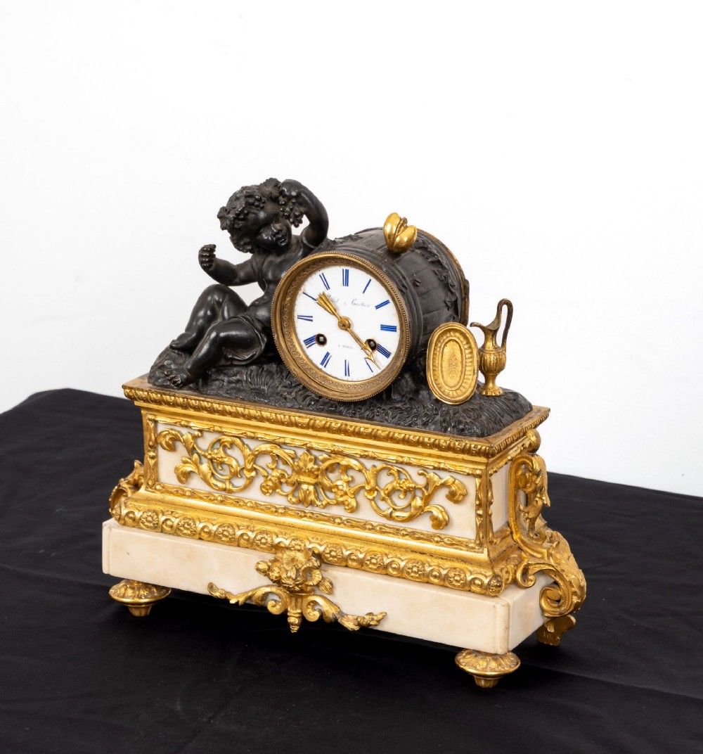 A French 19th-century figural mantel clock with a patinated bronze cherub beside a circular white enamel dial on a gilt-bronze and marble base. View V
