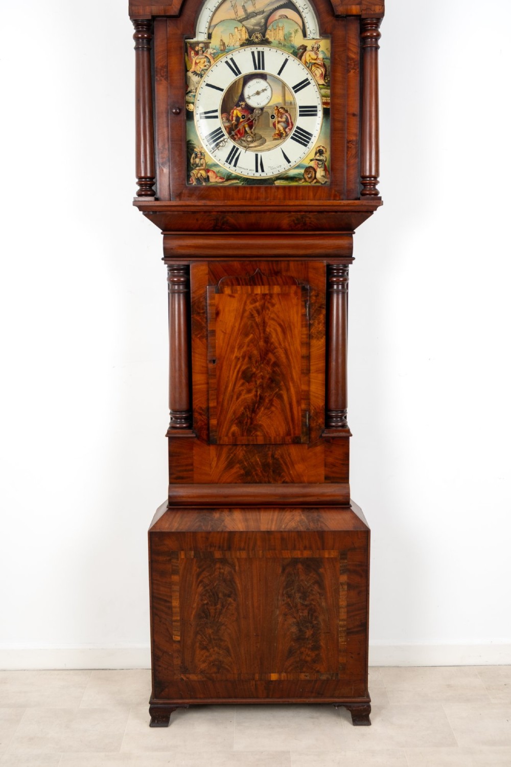 An antique mahogany longcase clock featuring a swan-neck pediment, turned columns, and a hand-painted arch dial with a moon phase display. View III