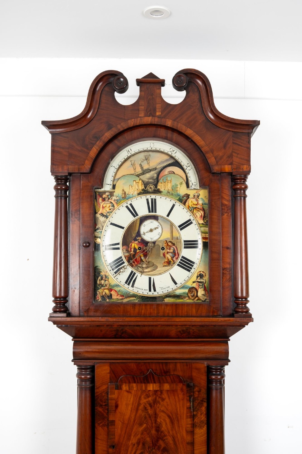 An antique mahogany longcase clock featuring a swan-neck pediment, turned columns, and a hand-painted arch dial with a moon phase display. View IV