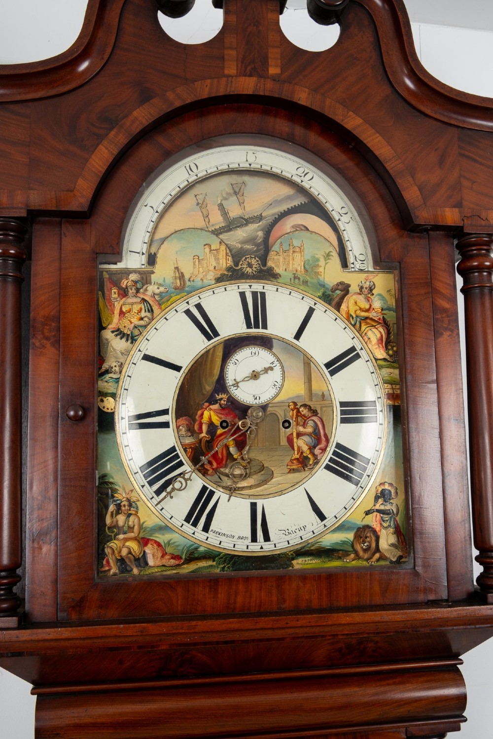 An antique mahogany longcase clock featuring a swan-neck pediment, turned columns, and a hand-painted arch dial with a moon phase display. View VIII