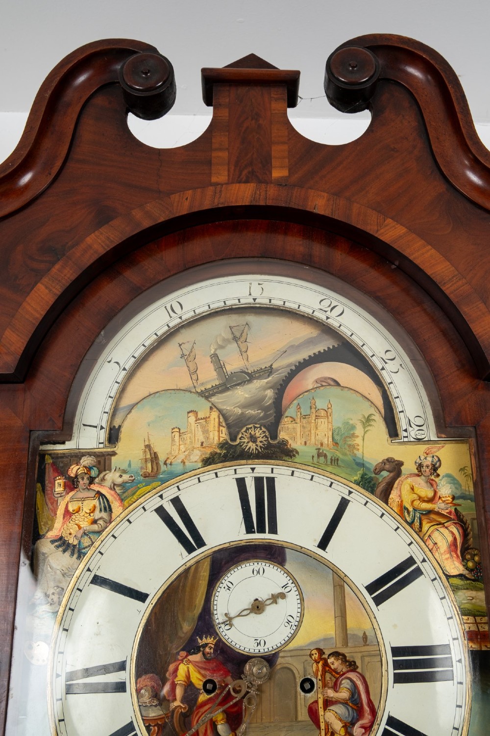 An antique mahogany longcase clock featuring a swan-neck pediment, turned columns, and a hand-painted arch dial with a moon phase display. View IX