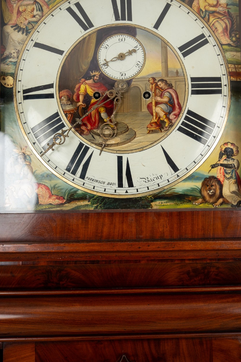 An antique mahogany longcase clock featuring a swan-neck pediment, turned columns, and a hand-painted arch dial with a moon phase display. View X