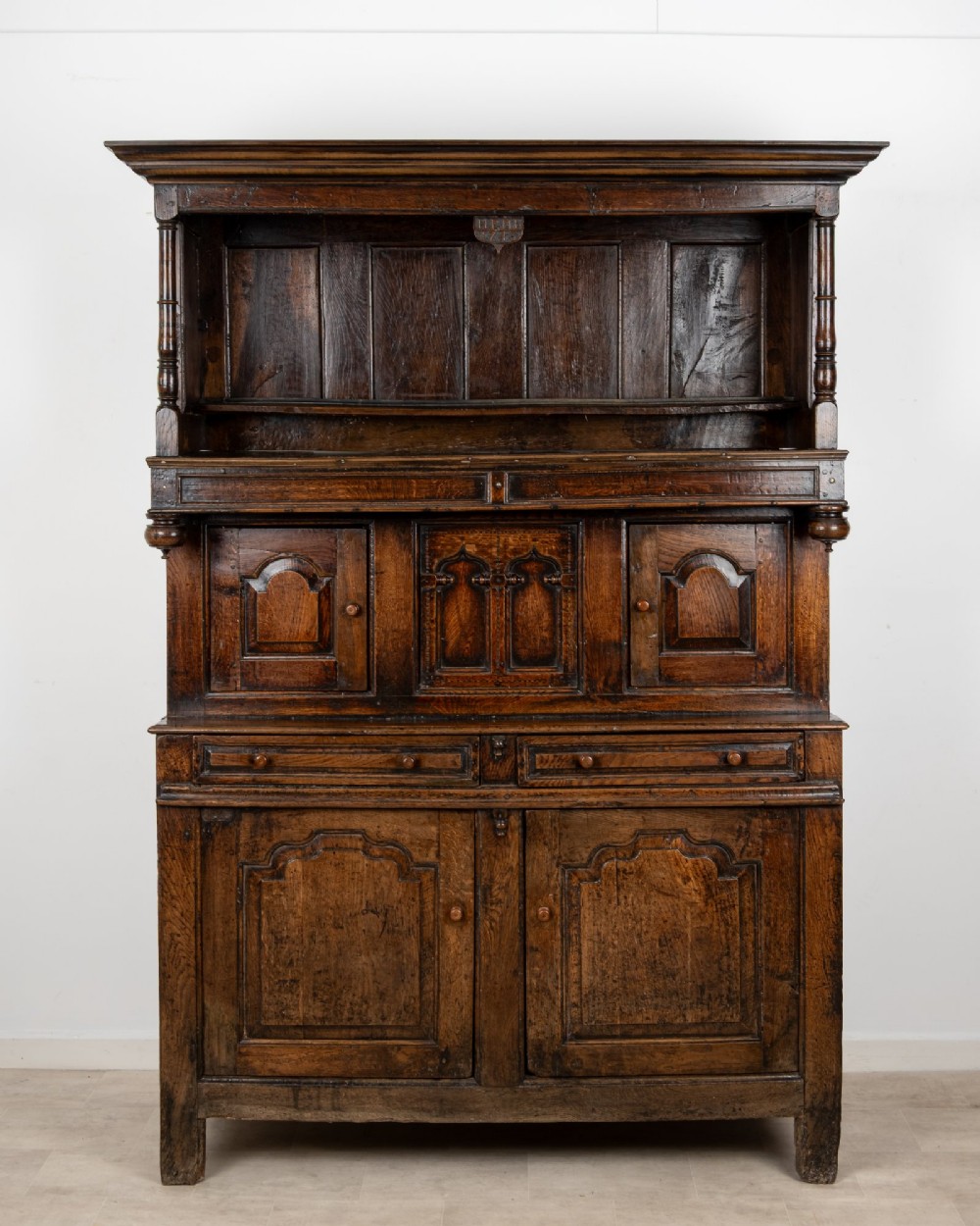 An 18th-century dark Welsh oak cwpwrdd tridarn three-tier press cupboard featuring fielded panels and turned canopy posts. View II