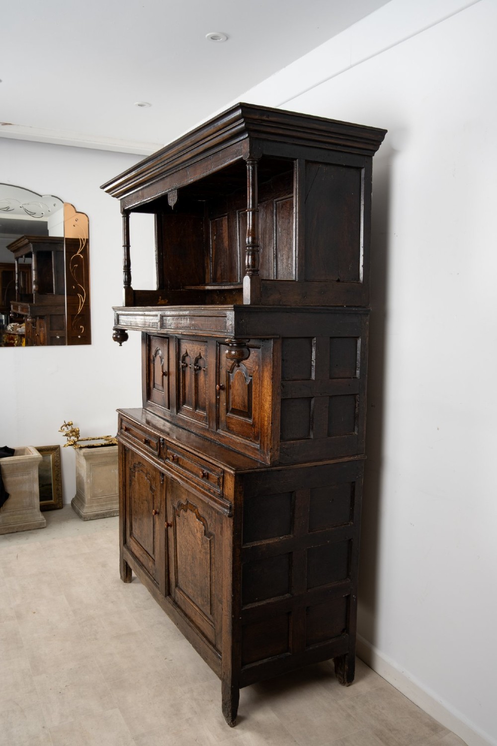 An 18th-century dark Welsh oak cwpwrdd tridarn three-tier press cupboard featuring fielded panels and turned canopy posts. View VI