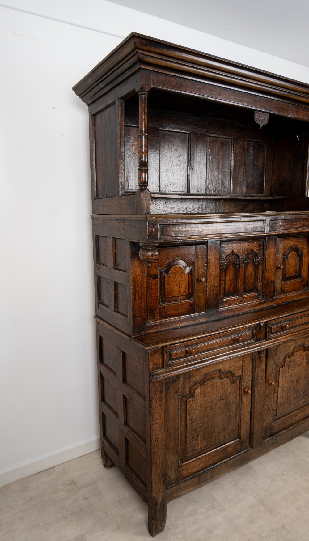 An 18th-century dark Welsh oak cwpwrdd tridarn three-tier press cupboard featuring fielded panels and turned canopy posts. View VII