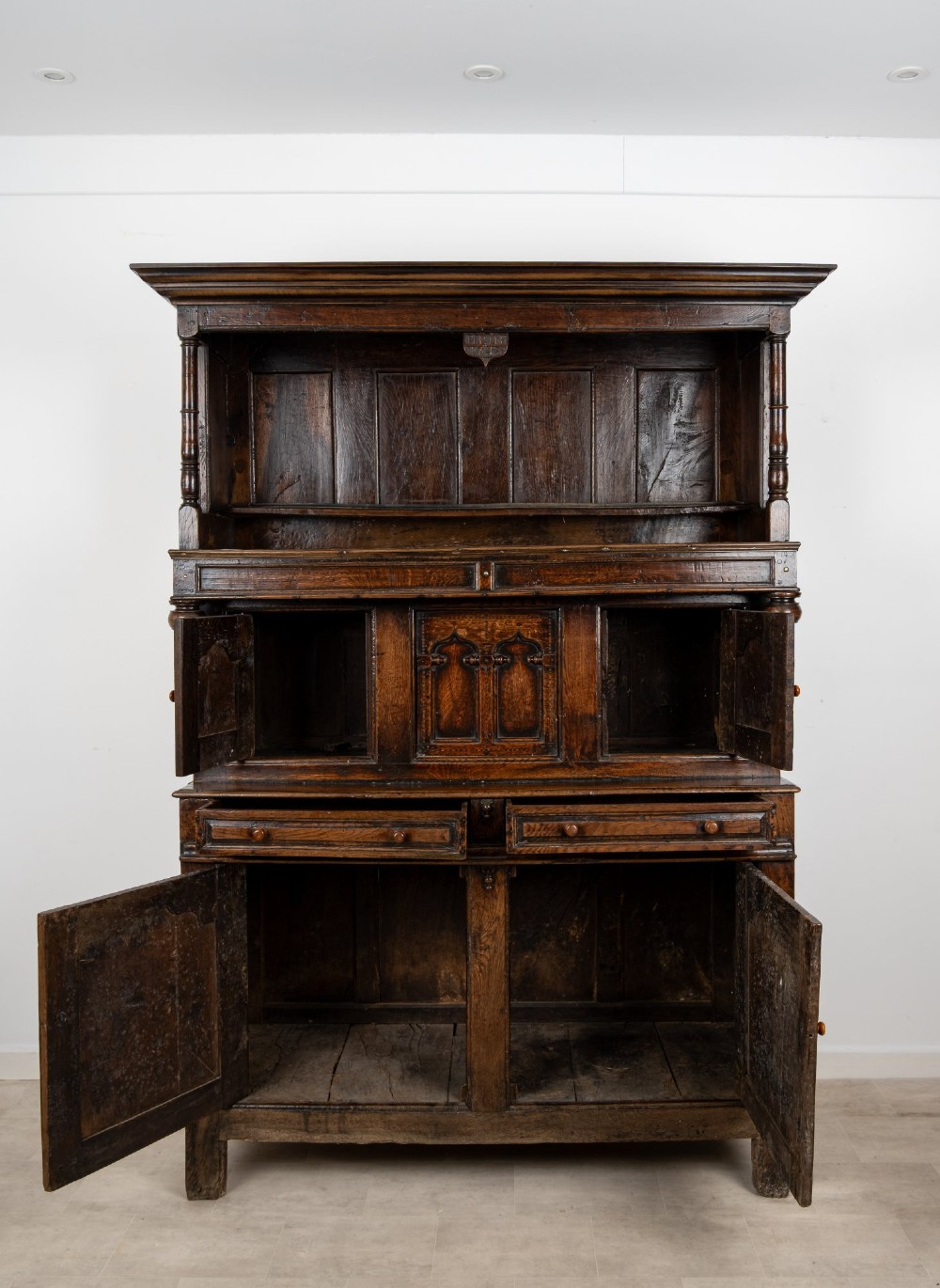An 18th-century dark Welsh oak cwpwrdd tridarn three-tier press cupboard featuring fielded panels and turned canopy posts. View VIII