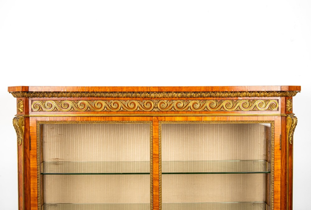 A large veneered display cabinet featuring gilt-bronze mounts, glazed twin doors, glass shelving, and a fabric-lined interior. View III