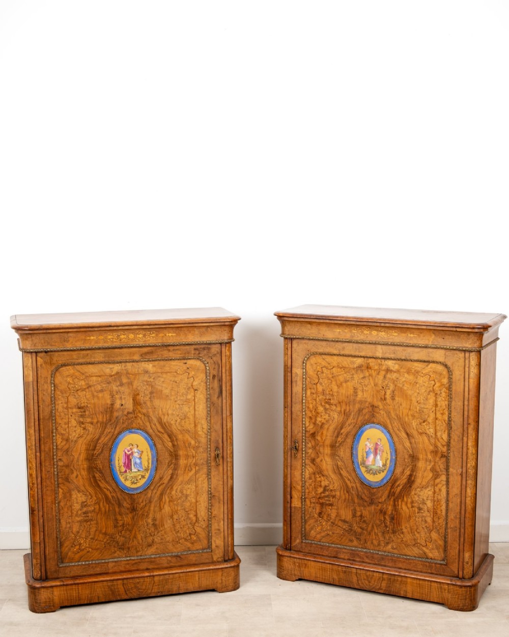 A pair of Victorian burr walnut side cabinets featuring inlaid boxwood detailing, gilt metal trim, and central oval blue porcelain plaques painted with classical figures. View II