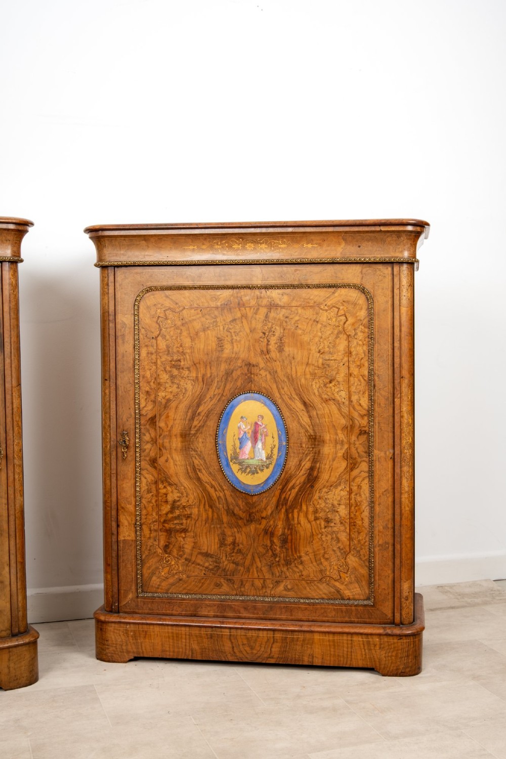 A pair of Victorian burr walnut side cabinets featuring inlaid boxwood detailing, gilt metal trim, and central oval blue porcelain plaques painted with classical figures. View IV