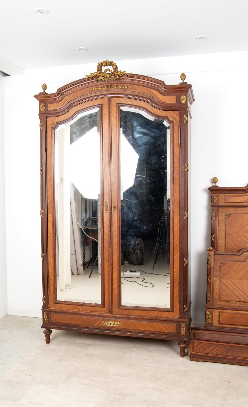 A French Louis XVI Revival mahogany bedroom suite comprising a mirrored two-door armoire, a matching bedframe with parquetry detailing, and a marble-topped bedside table with gilded bronze mounts. View II